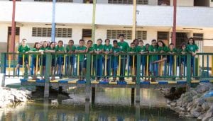 cbc students standing on bridge in front of classroom building at CBC smiling