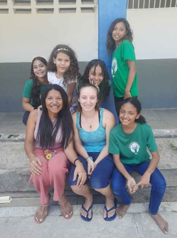American missionary with CBC teacher and students in front of classroom building.