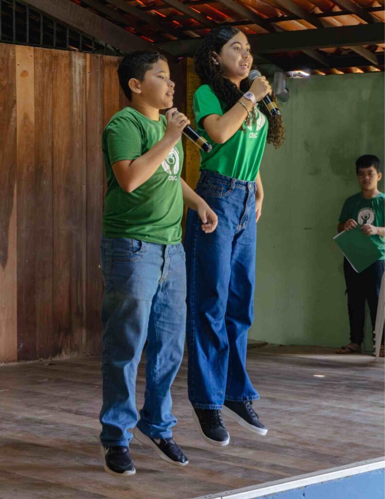 two CBC students jumping with excitement while singing into microphones