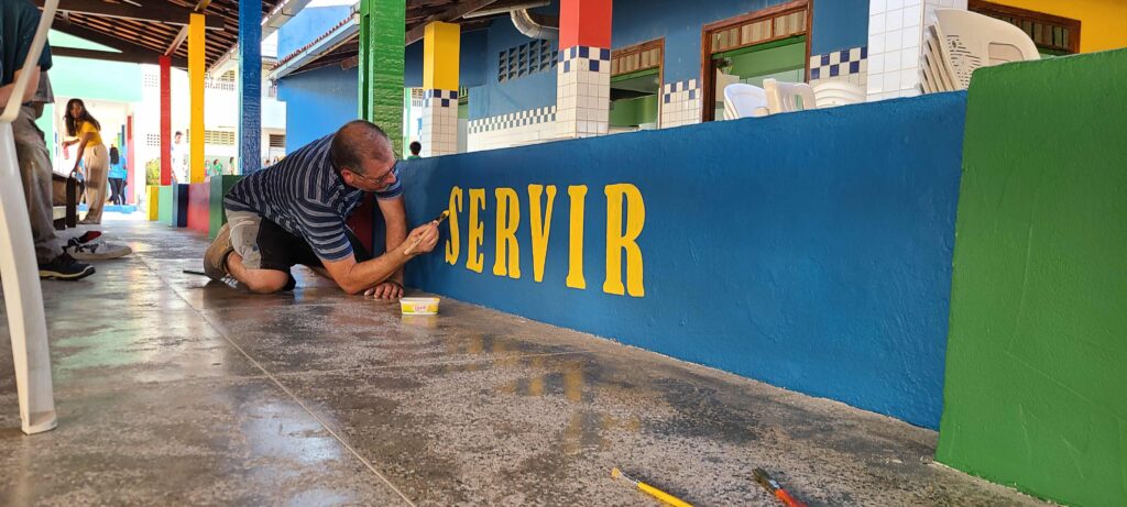 Man painting letters on a wall.