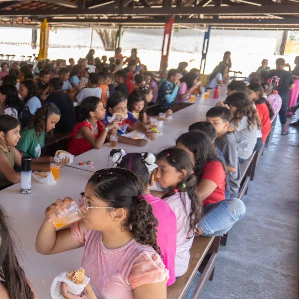 Children sitting at long tables at CBC eating a meal together